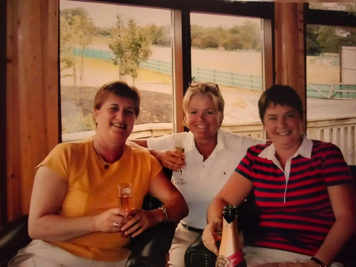 Older photo of three people sitting together by a window